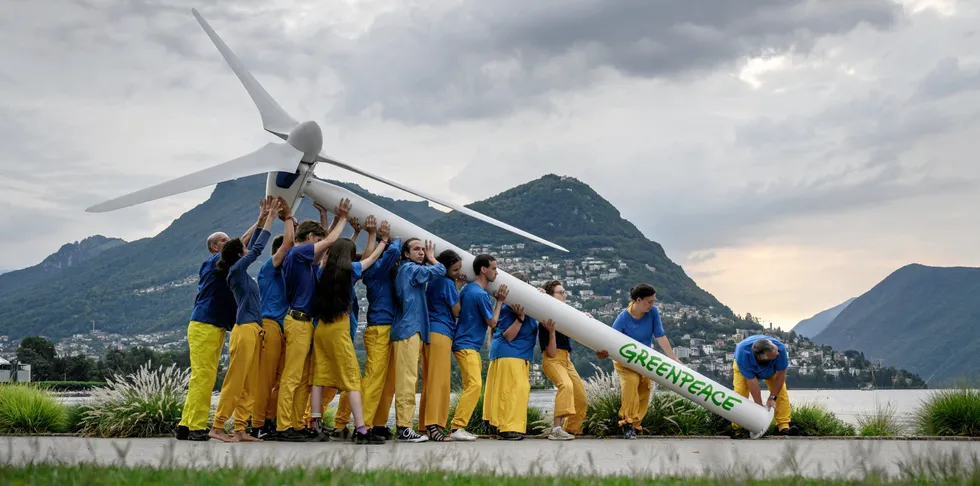 Greenpeace activists raise a model wind turbine on the edge of Lake Lugano during a demonstration calling for a sustainable reconstruction of Ukraine, ahead of a two-day Ukraine Recovery Conference in Lugano.
