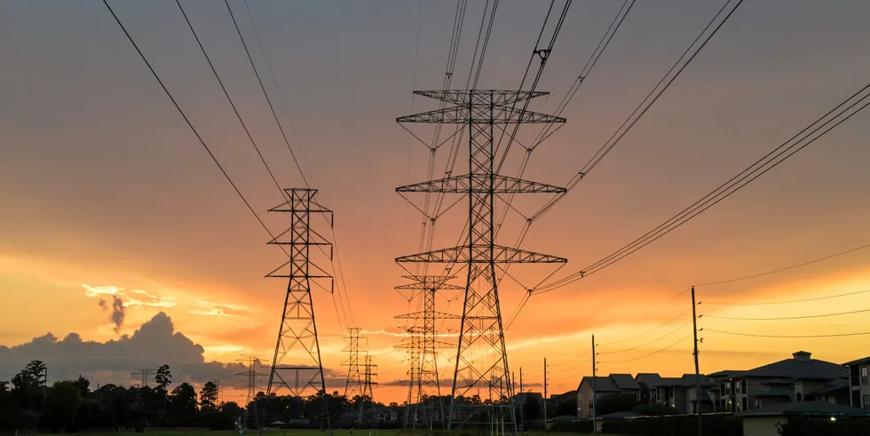 Group silhouette of transmission towers (power tower, electricity pylon, steel lattice tower) at sunset in Humble, Texas, US.