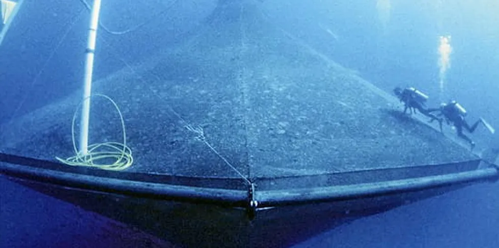 Divers clean the outside of SeaStation 3000, an open-ocean aquaculture project operated by the University of Hawaii.