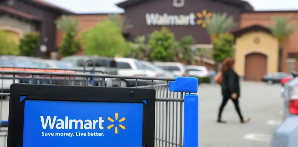 A woman walks past a shopping cart in the parking lot of a Walmart Supercenter in Rosemead, California.