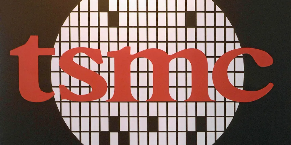 Taipei, TAIWAN: A woman walks past a logo of the TSMC, Taiwan Semiconductor Manufacturing Co.