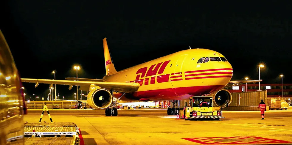 . A DHL airplane waits on the runway for air cargo loading.
