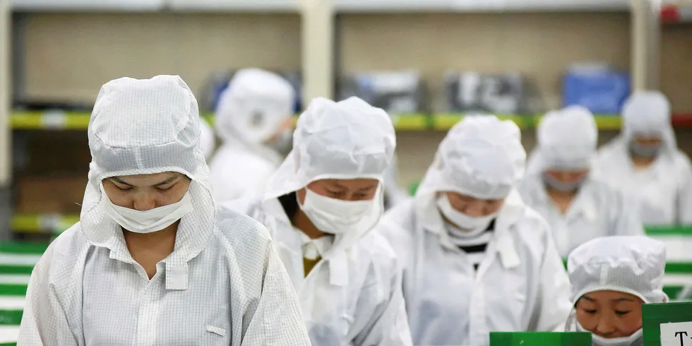 Employees perform final inspections on solar cells on the production line at the Trina Solar factory in Changzhou, China.