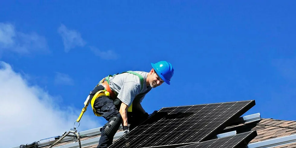 Man installing alternative energy photovoltaic solar panels on roof