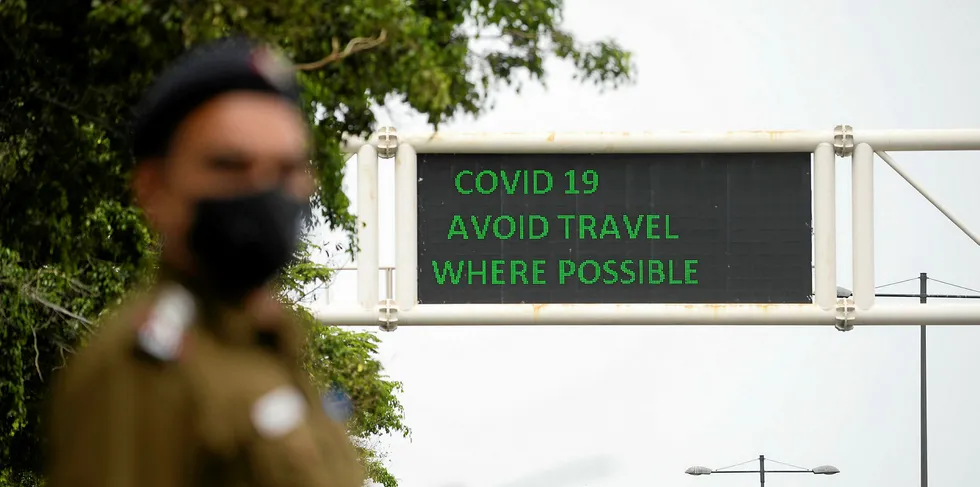 A policeman wearing a facemask stands along a roadsign informing of travel recommendations during a government-imposed nationwide lockdown as a preventive measure against the COVID-19 coronavirus in New Delhi.