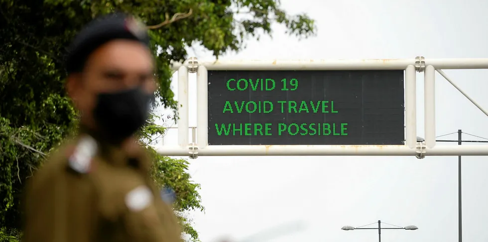 A policeman wearing a facemask stands along a roadsign informing of travel recommendations during a government-imposed nationwide lockdown as a preventive measure against the COVID-19 coronavirus in New Delhi on March 26, 2020.