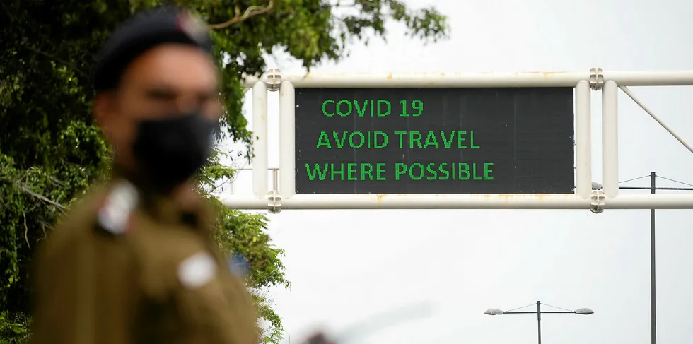 A policeman wearing a facemask stands along a roadsign informing of travel recommendations during a government-imposed nationwide lockdown as a preventive measure against the COVID-19 coronavirus in New Delhi.