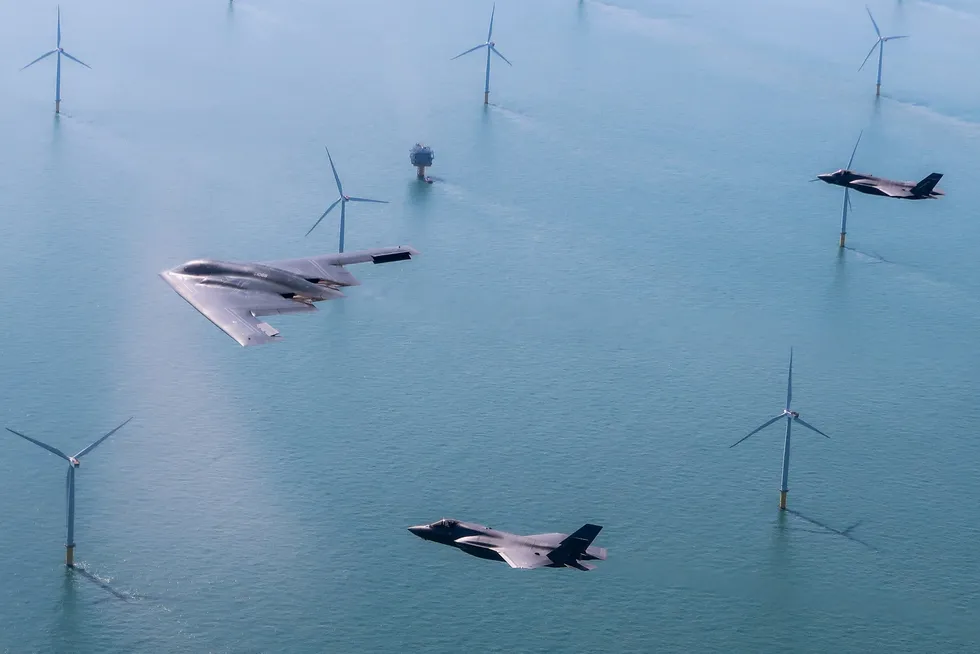 A US Air Force stealth bomber flies above a UK wind farm with two RAF F-35 jets.