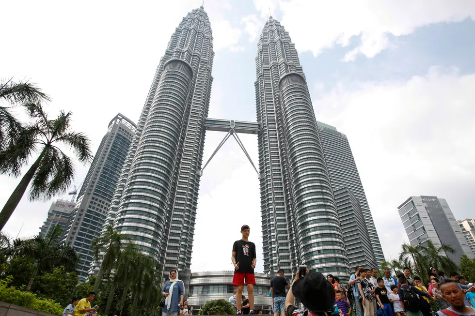 Tourists take souvenir photographs of Malaysian landmark, the Petronas Twin Towers, in Kuala Lumpur.