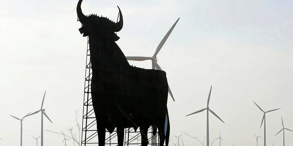 An Osborne bull in front of wind turbines in La Muela, Spain