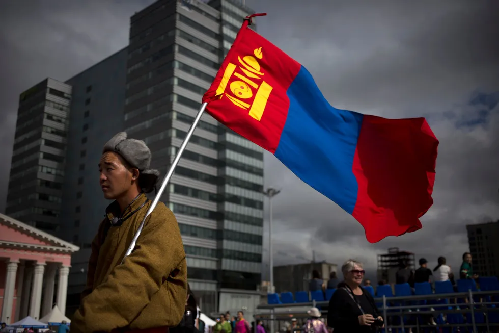 A man holds a Mongolian flag as he walks across Sukhbaatar Square in the capital city, Ulaanbaatar, in 2016.