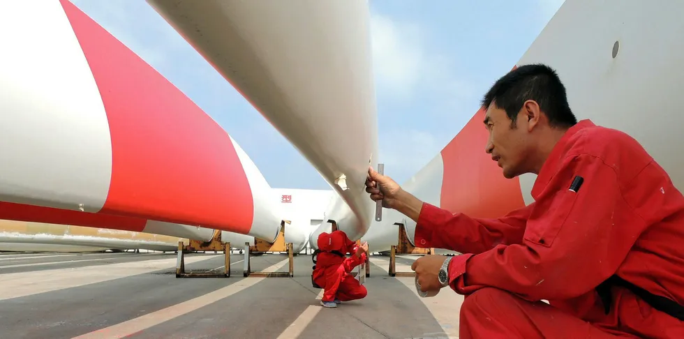 Labourers check the quality of blades of wind turbines in a factory in Lianyungang, in China's Jiangsu province