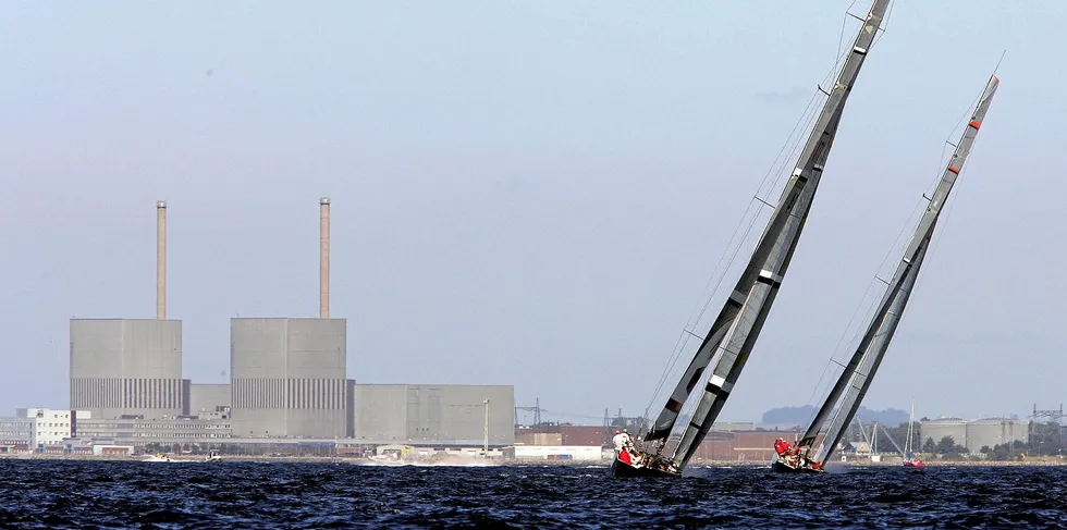 A yacht catches the wind with the closed down nuclear powerstation at Barseback, outside Malmo, behind.