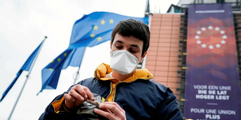 A man wearing a face mask as a preventive measure smokes in front of the EU headquarters in Brussels on March 16, 2020.