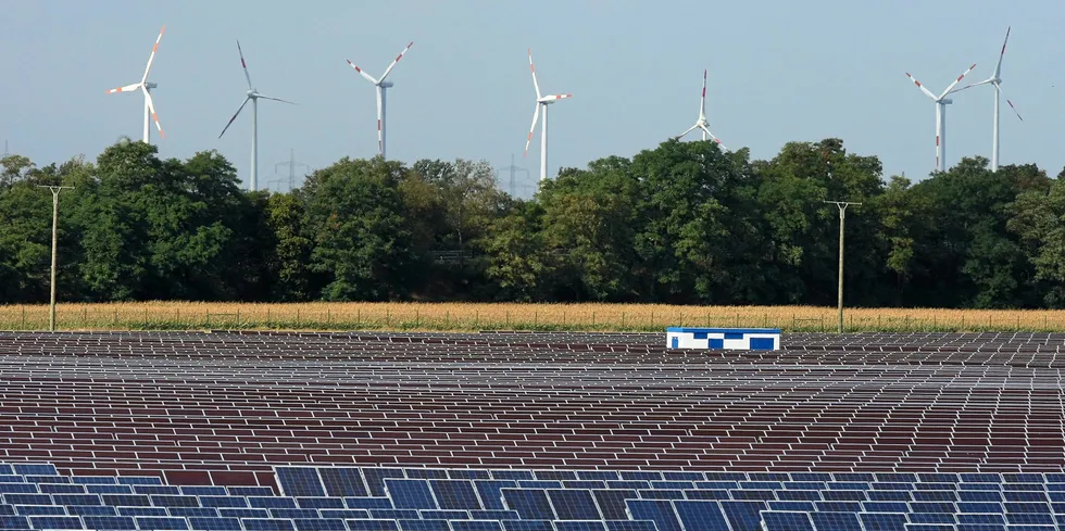 Wind turbines behind a PV farm near the headquarters and production facilities of German solar cell maker Q-Cells
