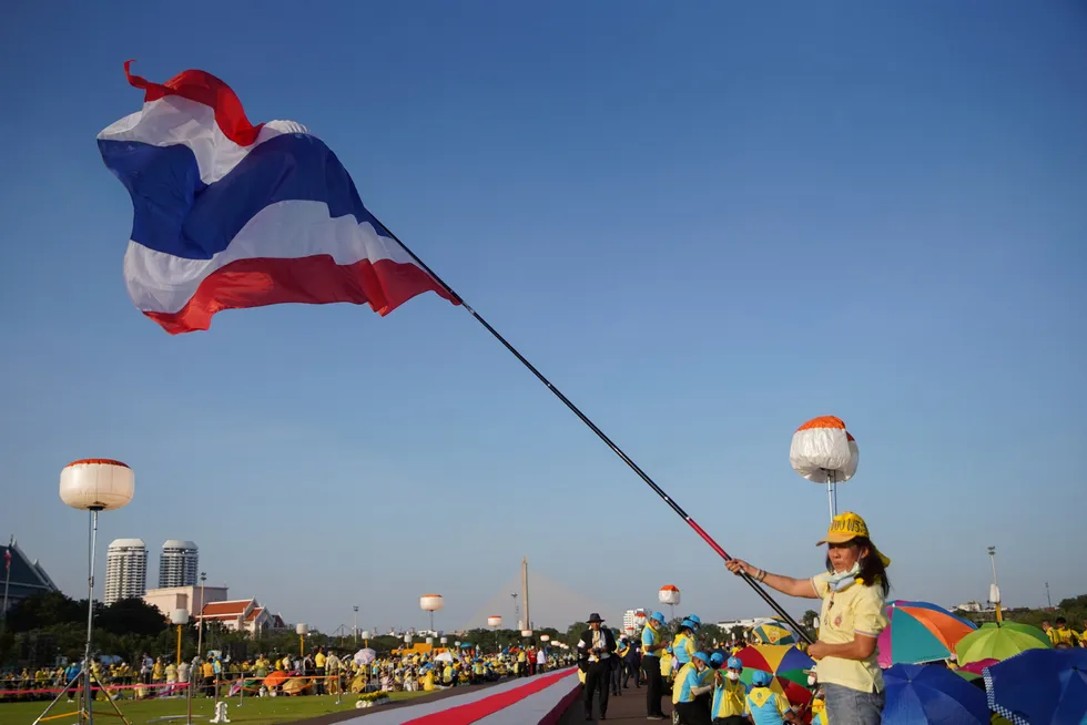 Development: A Thai woman waves the national flag outside the Grand Palace in Bangkok