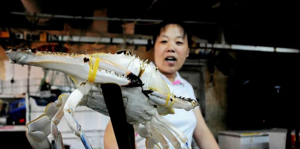 A vendor holds a crab as she waits for customers at a seafood market in Qingdao, in eastern China's Shandong province.