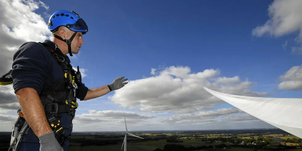 A technician of the French multinational electric utility company Engie stands on the top of a windmill during an inspection