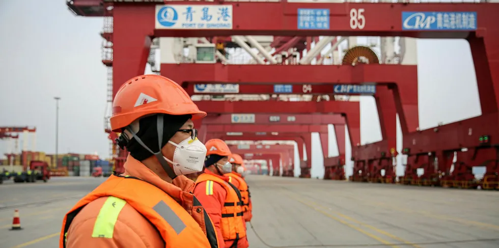 Chinese employees wearing protective facemasks working at a port in Qingdao in China's eastern Shandong province.