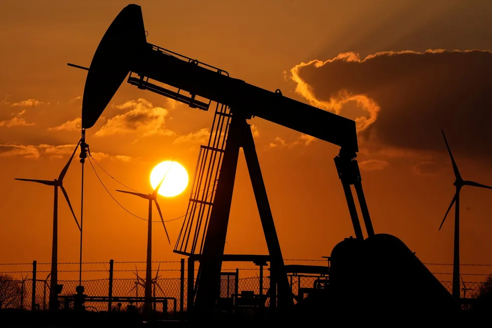 A pump jack extracts crude oil at an oil field near wind turbines in Emlichheim, Germany, March 18, 2022.