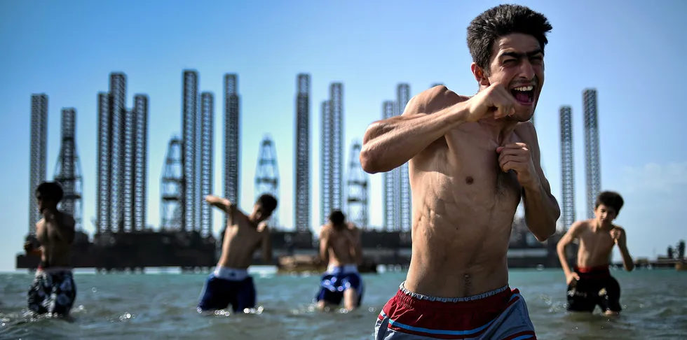 Teenagers from a Baku boxing school take part in a training session in the Caspian Sea with oil rigs in the background