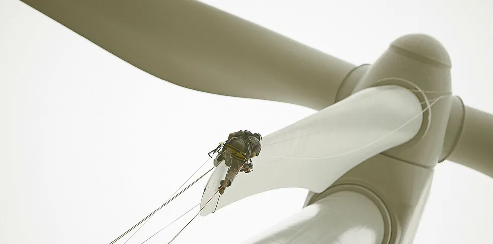 Wind turbine service technician inspects tip of a rotor blade