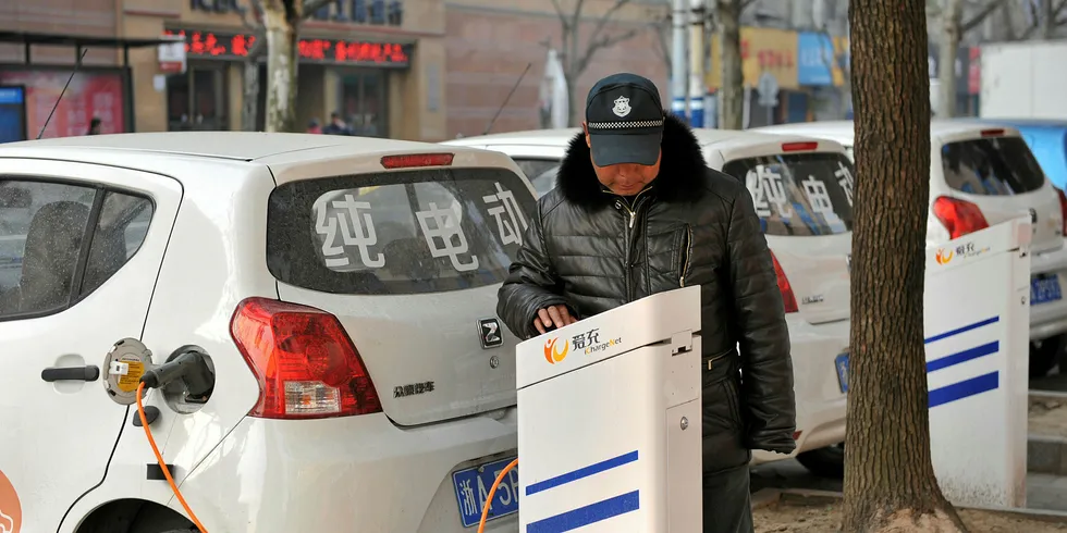 A man charging an EV at a charging point in Linan, Zhejiang province, China.