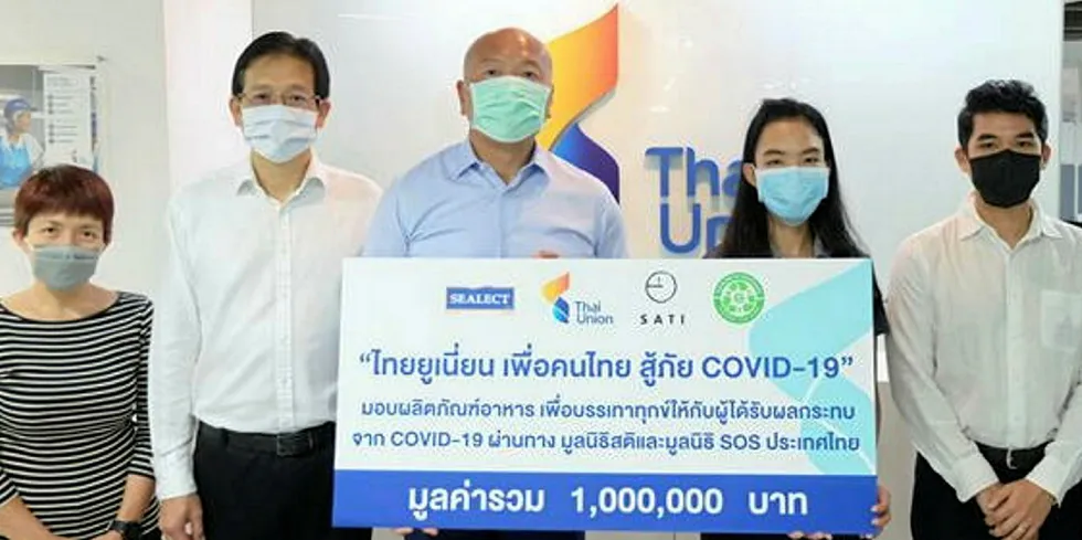 Thiraphong Chansiri, CEO of Thai Union Group, stands with colleagues as they present a donation of tuna to Thai communities impacted by coronavirus.