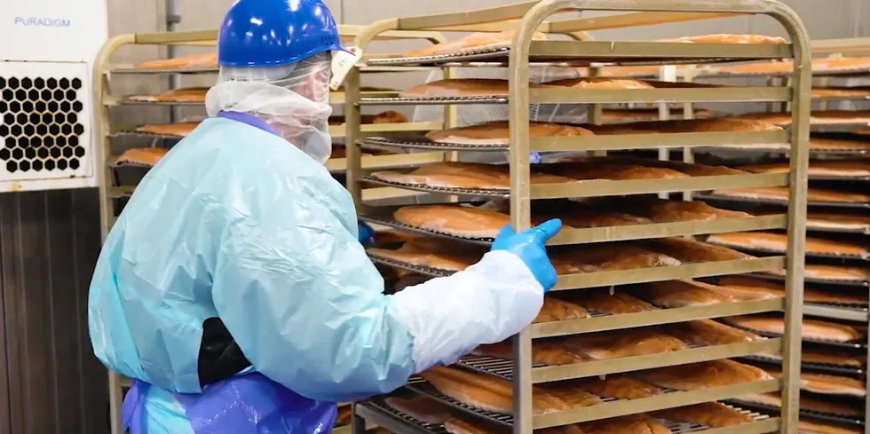 A worker at a Honey Smoked Fish Co. facility handles a tray of smoked salmon. The company announced it had sold off its Miami cold smoked salmon facility in early May.
