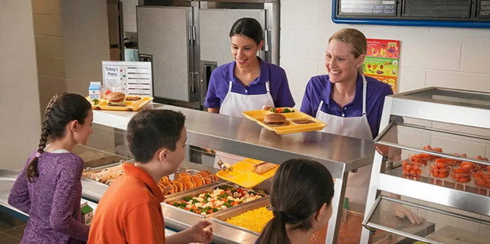 School Nutrition Professionals offering school lunch to students at the serving line.
