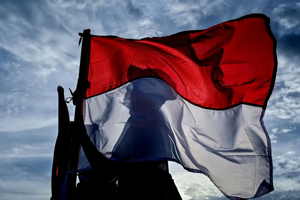 A man holds the Indonesian national flag at a beach in Banda Aceh, Indonesia.