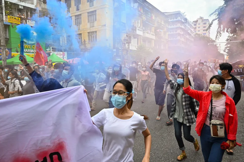 Power of three: pro-democracy protesters make the three-fingered salute and hold flares during an anti-military rally in Yangon this week