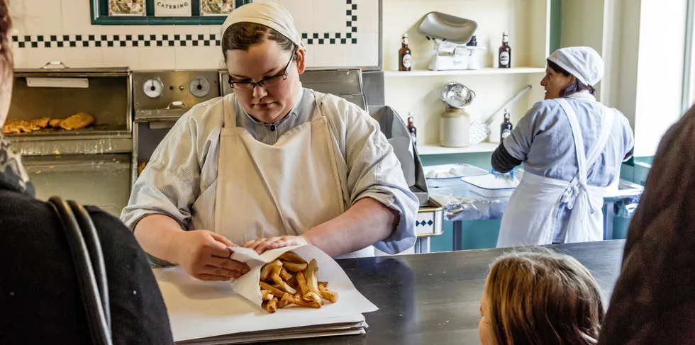 A woman dressed in traditional costume serves fish and chips to visitors at Blists Hill Victorian Museum in Ironbridge.