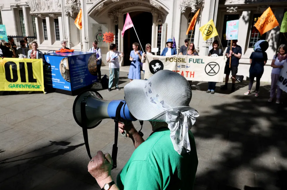 A person uses a megaphone as climate activists await a ruling on whether planning permission granted for oil wells in southern England was lawful, outside the Supreme Court in London on 20 June 2024.