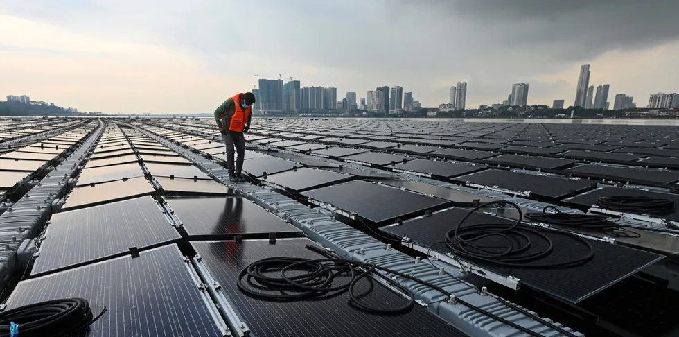 This photograph shows a worker checking cables on a floating solar power farm at sea, off Singapore's northern coast just across the Malaysian state of Johor.