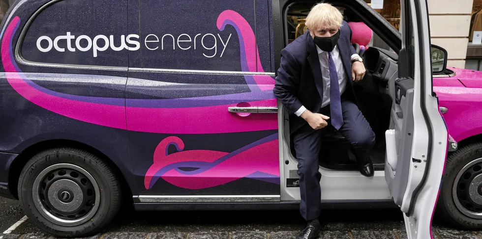 Britain's Prime Minister Boris Johnson gets out of a a branded electric taxi during a visit to the HQ of Octopus Energy in London.