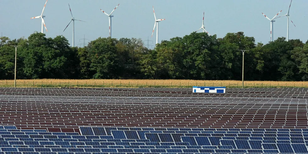 Wind turbines spin behind a field of solar cell panels near Bitterfeld, Germany