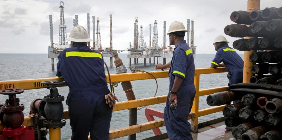 Crew members look over idle oil rigs in the Gulf of Mexico near Port Fourchon, Louisiana