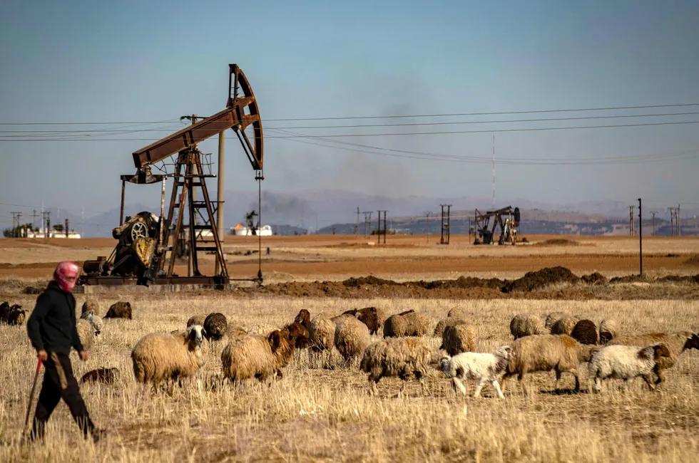 A shepherd walks past the Rmailan oilfield in northeast Syria, near the border with Turkey, on Wednesday. On Monday, the US eased sanctions relating to essential energy services in Syria as the Middle East country seeks to rebuild following December’s collapse of President Bashar al-Assad’s regime.