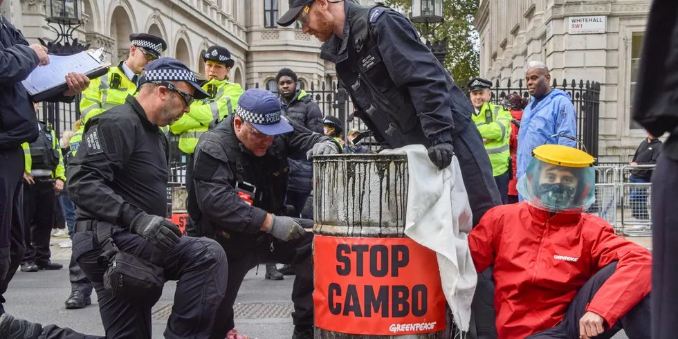 Police officers cut through a barrel to remove an activist during a Stop Cambo protest.