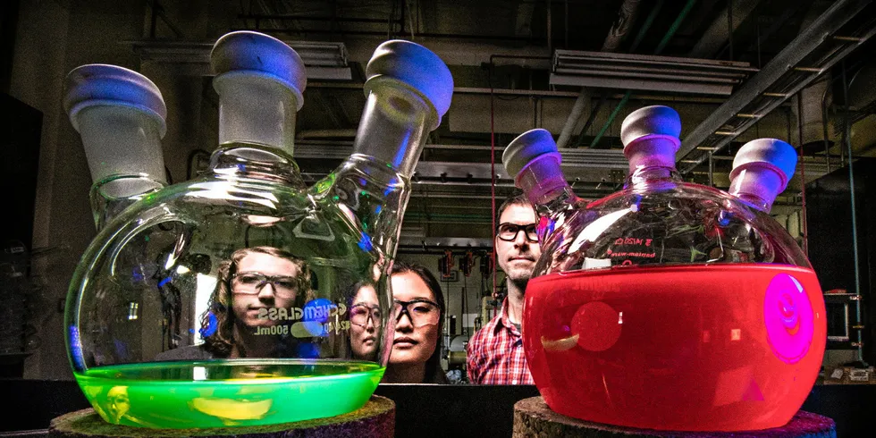 National Renewable Energy Laboratory researchers with solutions of all-inorganic perovskite quantum dots, showing intense photoluminescence when illuminated with UV light