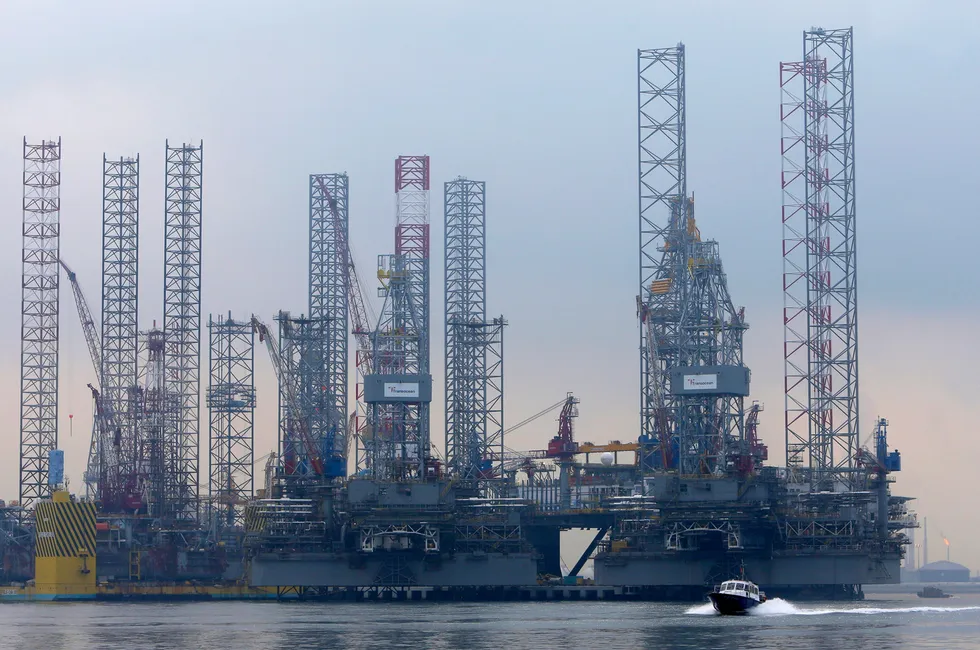 A vessel speeds past drilling rigs at Keppel Fels shipyard in Singapore in September 2012.