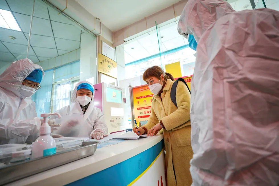 Virus fears: Medical workers in protective gear talk with a woman suspected of being ill in central China's Hubei Province