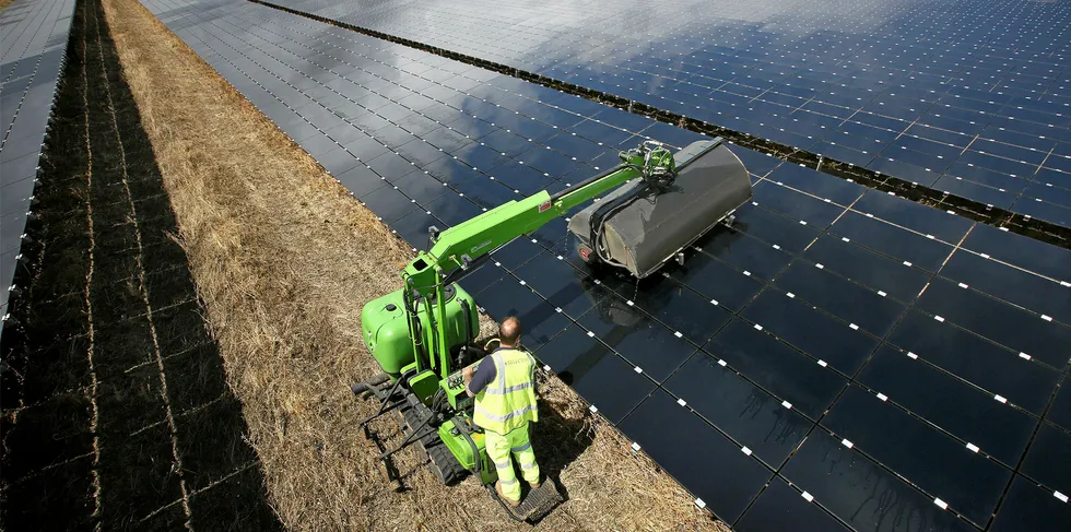A workman uses a machine to clean panels at the Landmead solar farm near Abingdon, England.