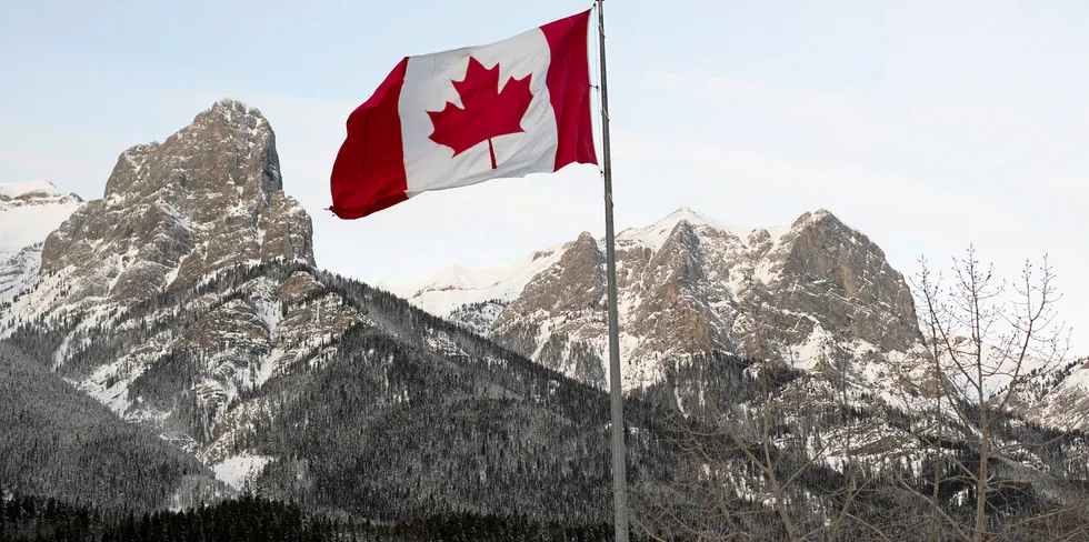 The Canadian flag flies over the Canadian Rockies