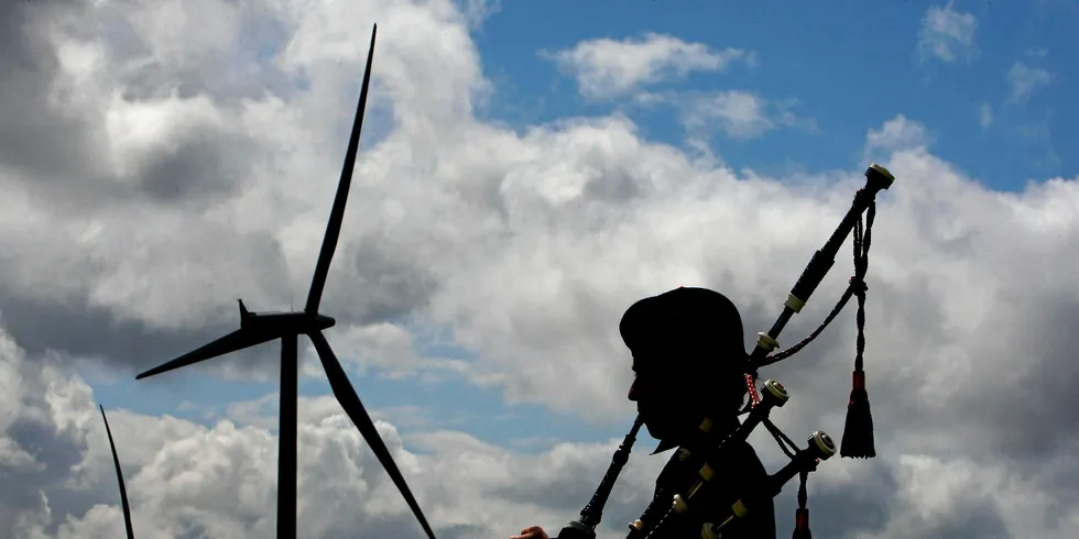 A piper plays at the Whiteless wind farm in Scotland