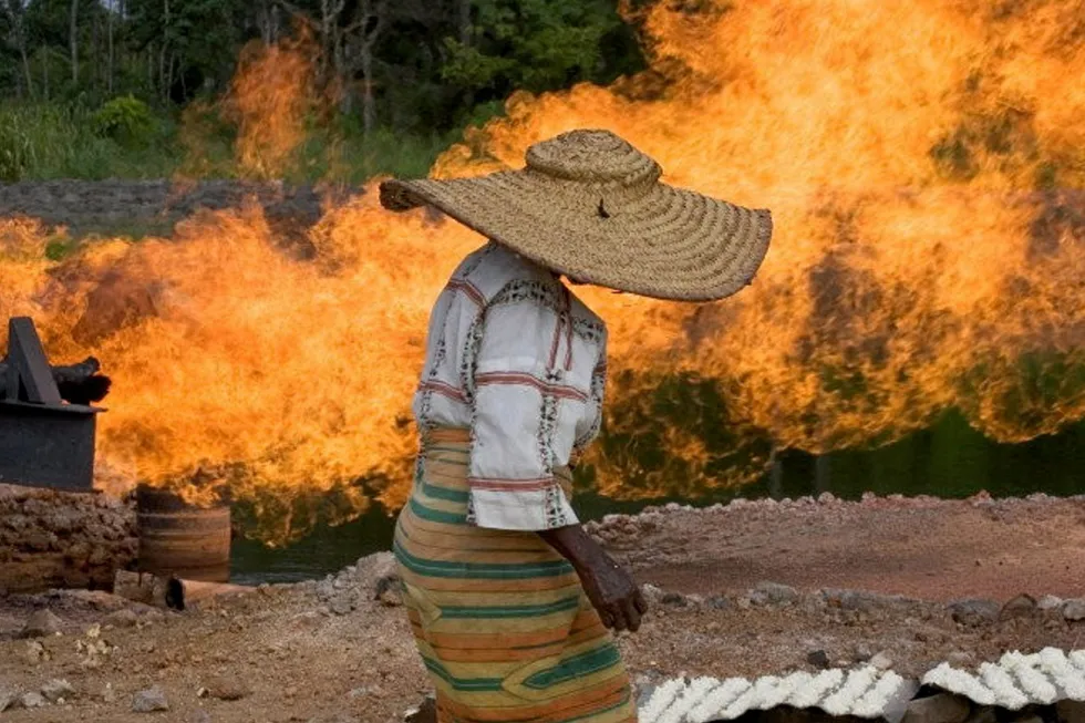 Hazardous: a woman walks in close proximity to a natural gas flare in NIgeria