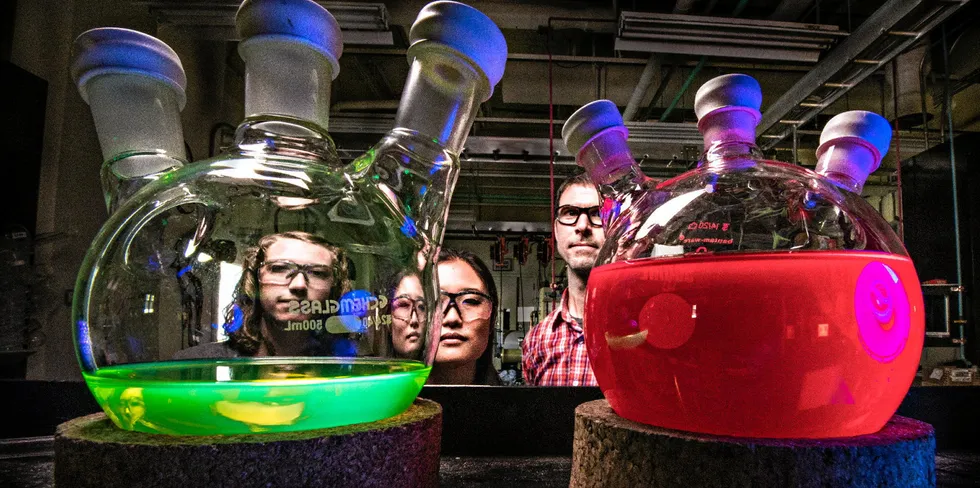 NREL researchers with solutions of all-inorganic perovskite quantum dots, showing intense photoluminescence when illuminated with UV light