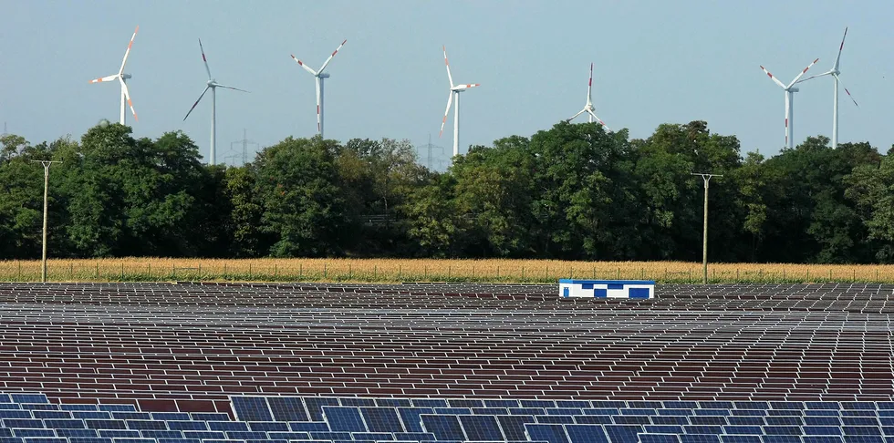 Wind turbines turn behind a PV array in Bitterfeld, Germany.
