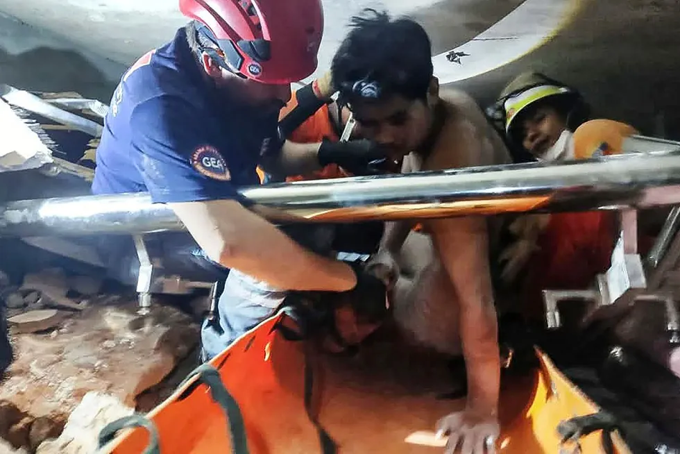 This photo taken and released on 2 April 2025 by the Myanmar Military Information Team shows a joint team of Myanmar and Turkish rescuers pulling a man alive from the rubble of a hotel in the capital Naypyidaw, five days after a major earthquake struck Myanmar.